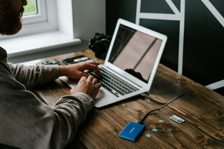 person in gray long sleeve shirt using macbook air on brown wooden table - External data on an external storage